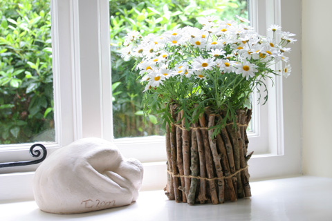 Twig flower pot with white flowers in front of a window