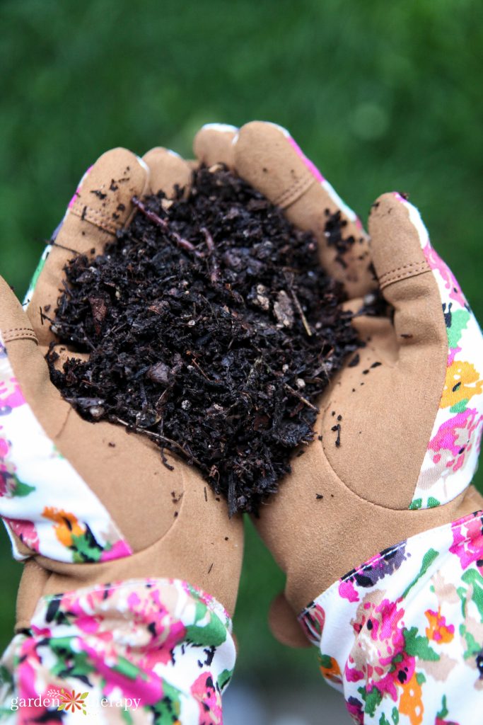 flowery garden gloves with a handful of compost