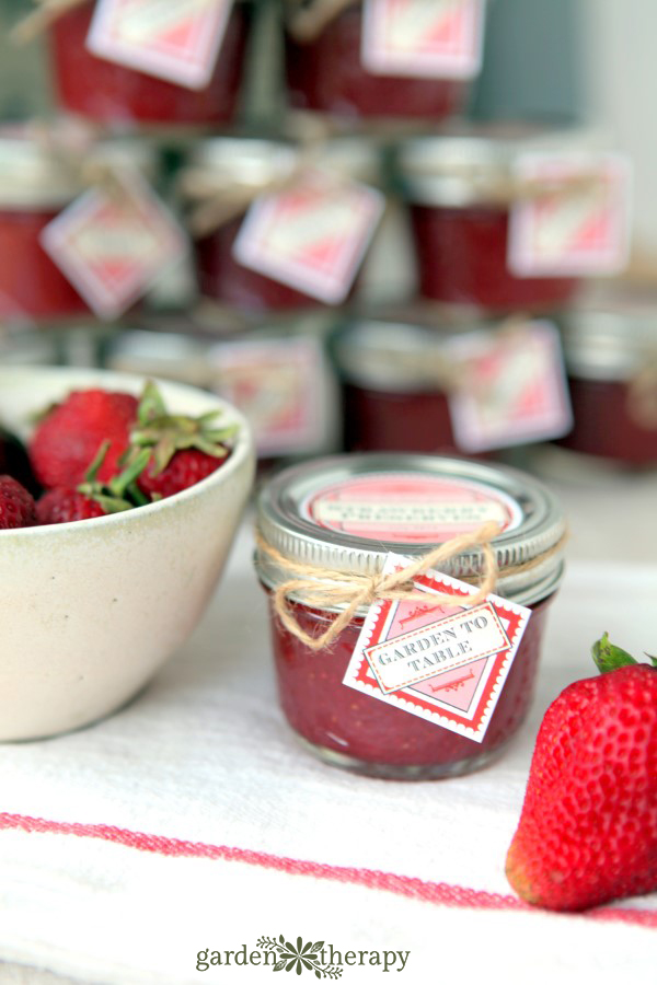 bowl of strawberries next to a jar of homemade strawberry jam