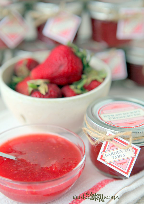 Low Sugar Strawberry Freezer Jam in a bowl with a white bowl of starwberries in the back