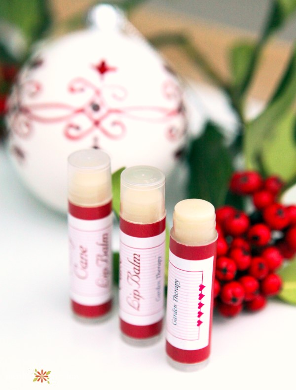 3 tubes of peppermint lip balm with an ornament and red berries out of focus in the backgrround