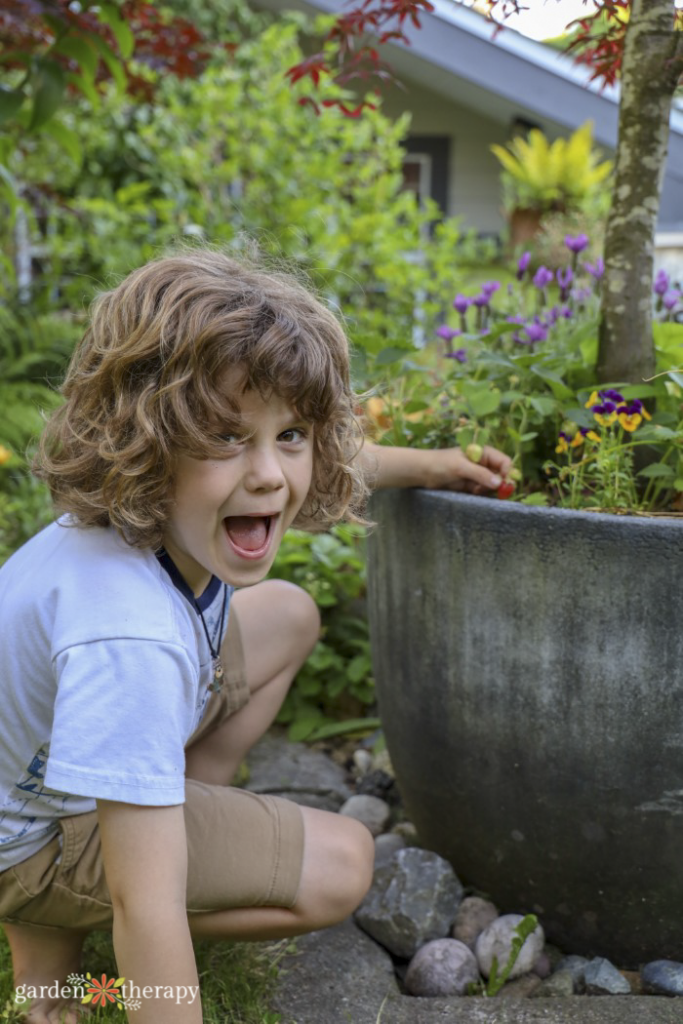 kid smiling and looking at camera while harvesting from the garden