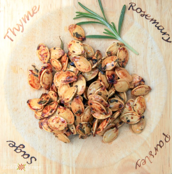 roasted pumpkin seeds with a sprig of rosemary and lettering around the edges reading "thyme, rosemary, parsley, sage"