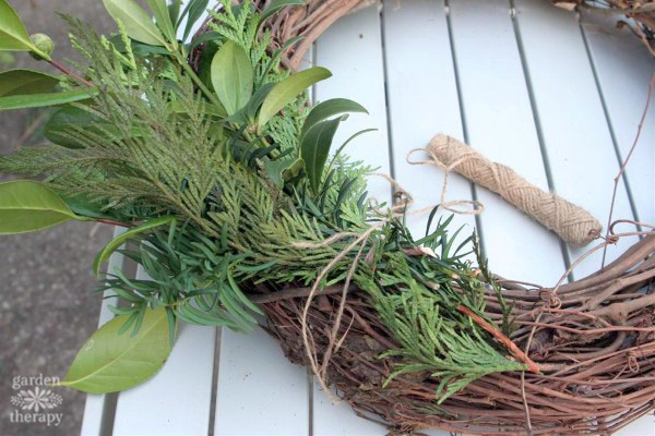 Adding fresh greens to a wreath form