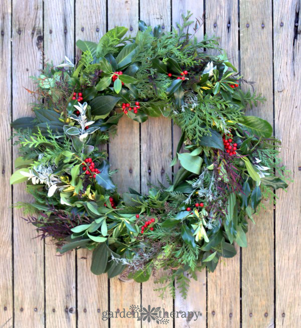 Evergreen greenery and red berry wreath on a fence