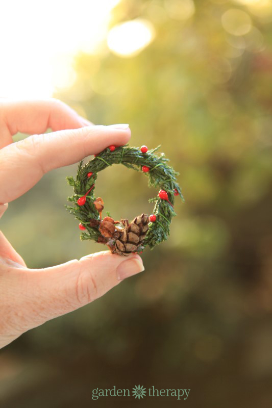 DIY miniature Christmas wreath held between thumb and index finger