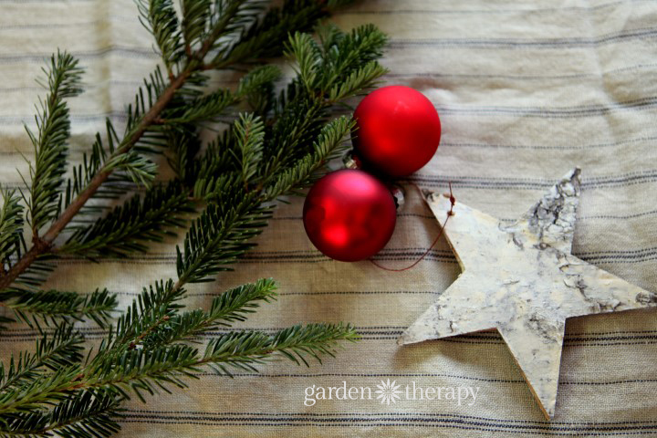 tablecloth with holiday decor including evergreen red glass ball and a birch star