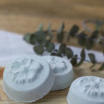 Flower-shaped shower steamers with eucalyptus leaves in background.