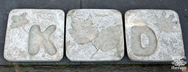 Piedras de jardín de cemento con letras y hojas como decoración