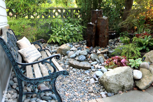 front yard garden with bench and a fountain surrounded by river rocks