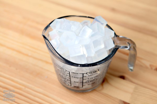 Pyrex measuring cup filled with cubes of clear melt and pour soap base.