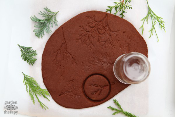 Cutting out shapes from cinnamon dough with a mason jar.