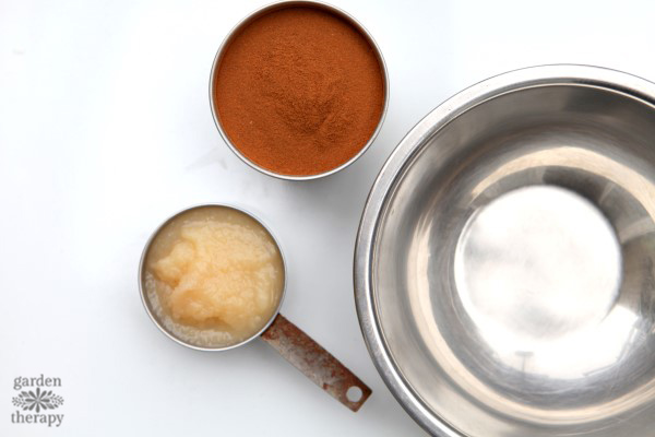 Apple sauce and cinnamon next to a metal bowl for cinnamon ornaments