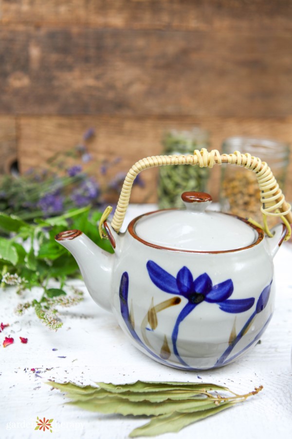 teapot next to fresh herbs for brewing