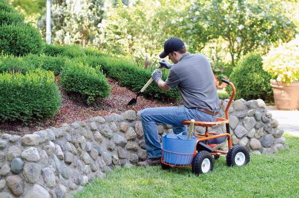 Man digging in the garden while seated in a wheeled garden seat