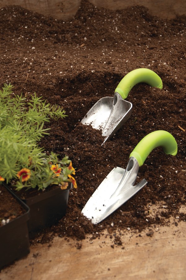 Two NRG Transplanters in a garden bed with flowers in nursery pots beside them.