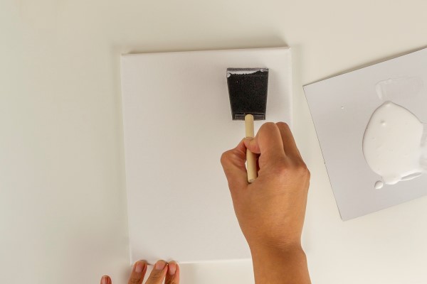 Applying decoupage glue to canvas with a foam brush