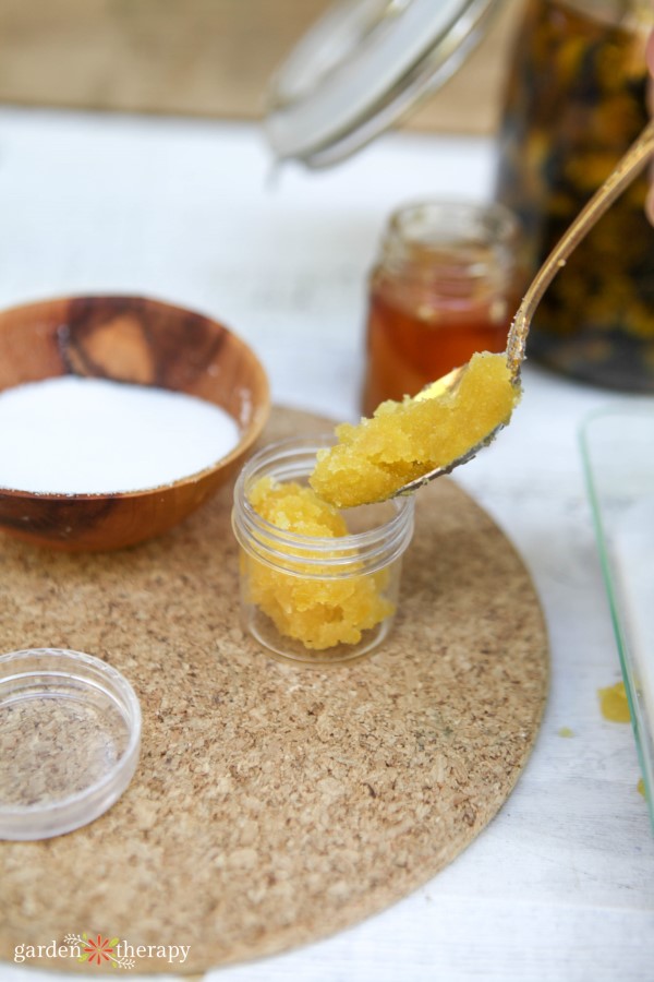 adding homemade lip scrub into a small jar