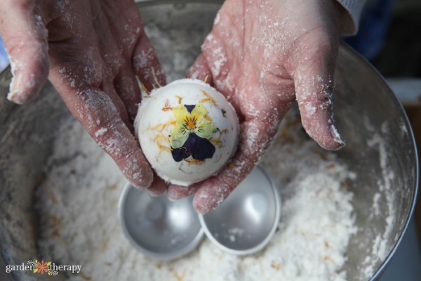 Woman making a bath bomb with dried flower petals