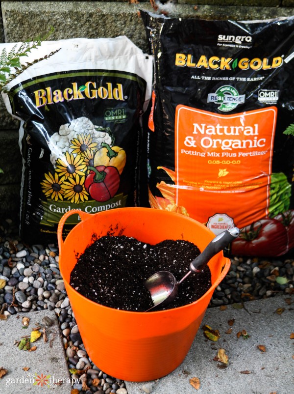 containers of black gold potting mix with an orange bucket for fall