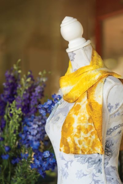 Yellow silk scarf dyed with marigold flowers draped over a dressform
