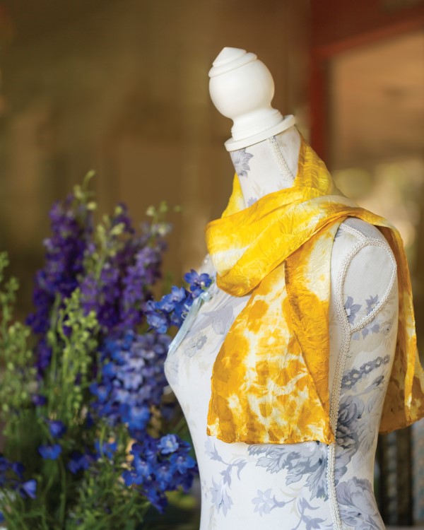 Yellow silk scarf dyed with marigold flowers draped over a dressform