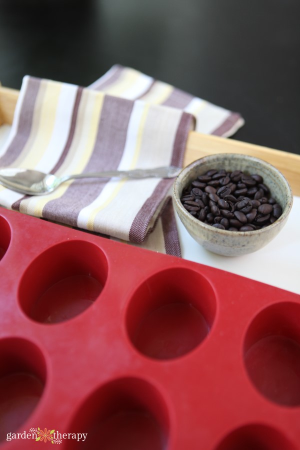 adding coffee beans to soap molds for massage bars