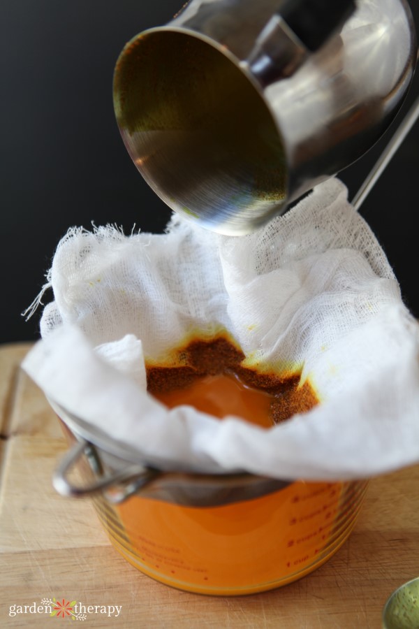 Straining the Warming Herbal Balm through Cheesecloth