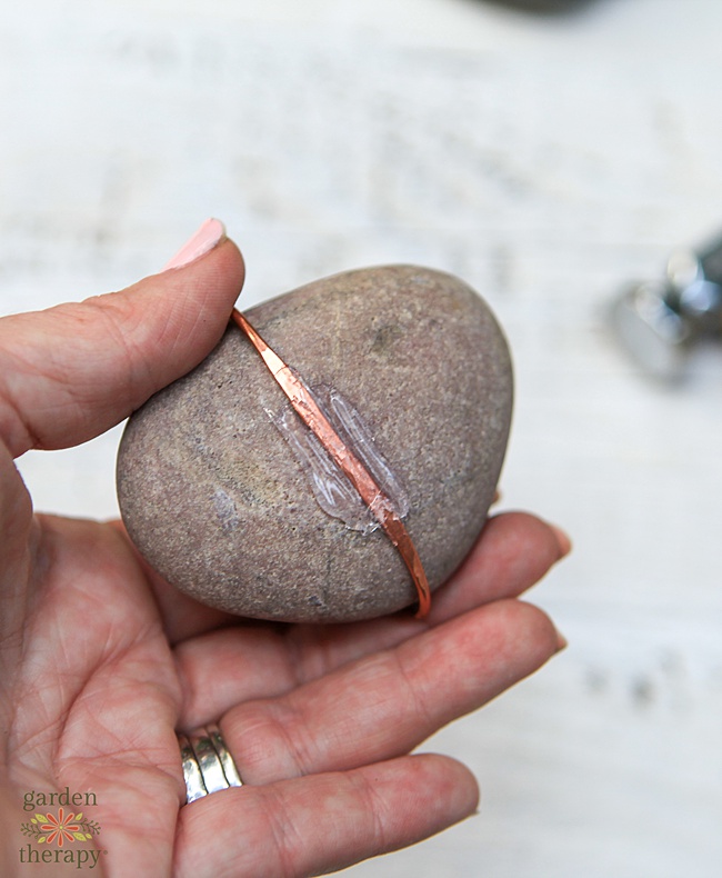 copper colored wire hot glued against the bottom 