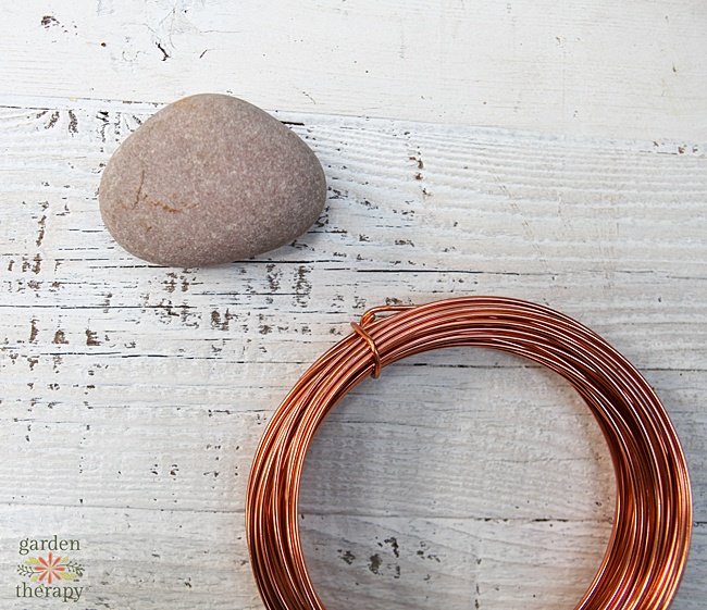 copper colored wire next to river stone