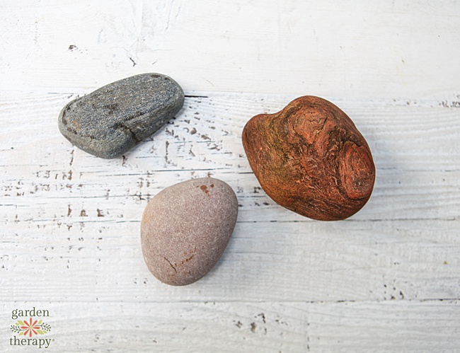 3 river stones on a white wood backdrop