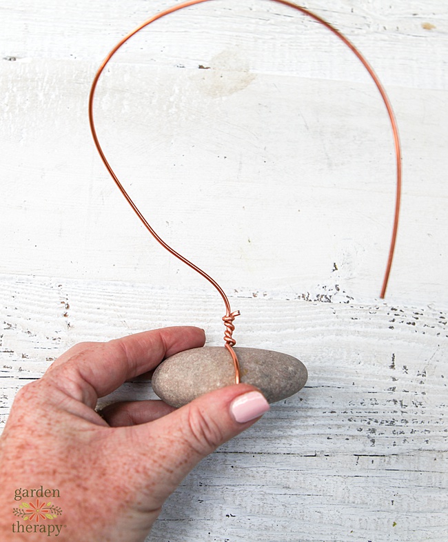 DIY air plant stand with copper colored wire wrapped around a rock