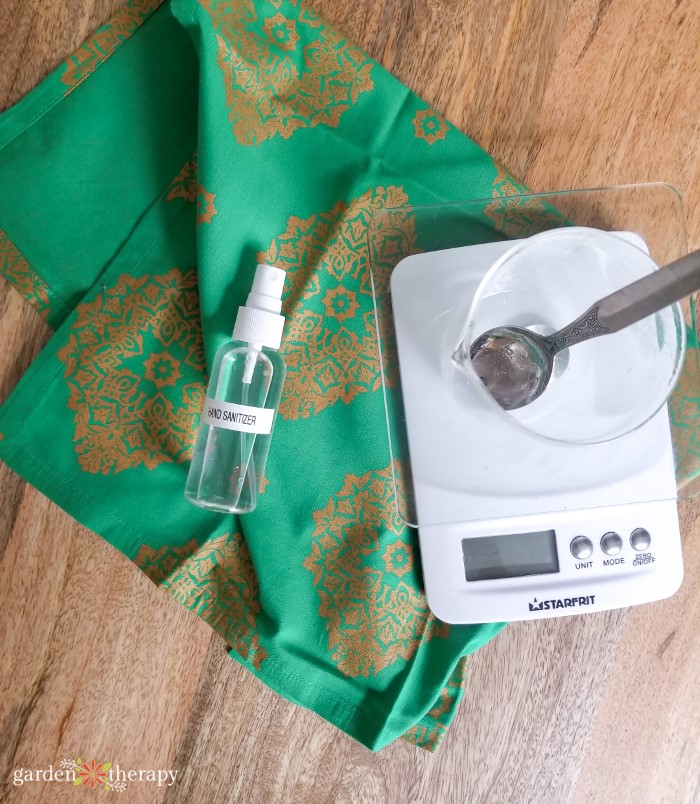 Spray bottle of homemade hand sanitizer next to a kitchen scale