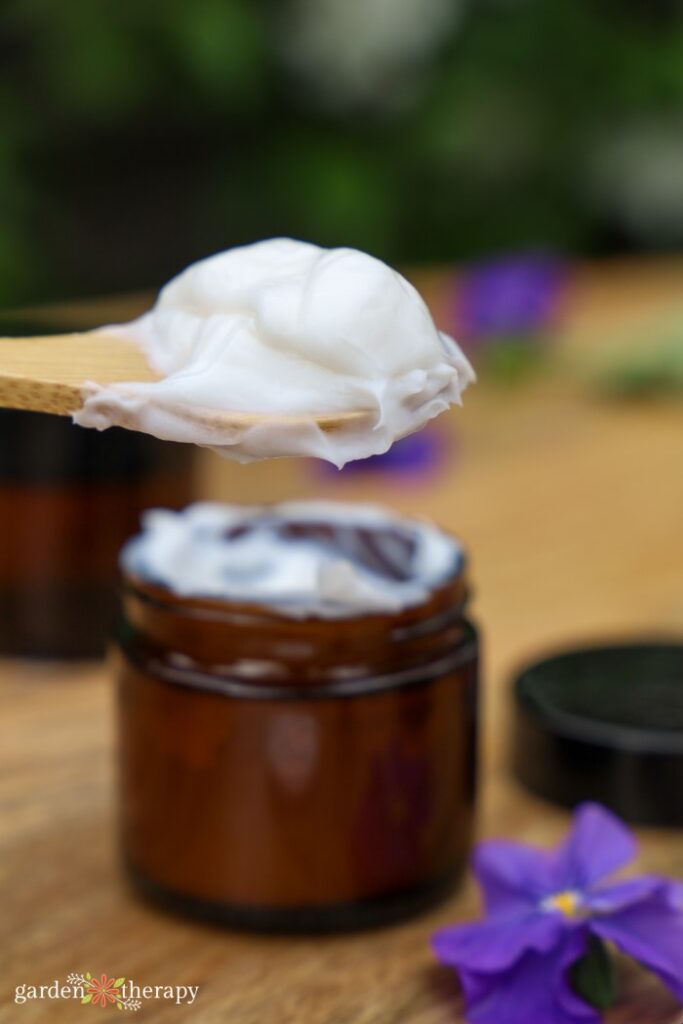 Scooping diy hand cream into a glass jar