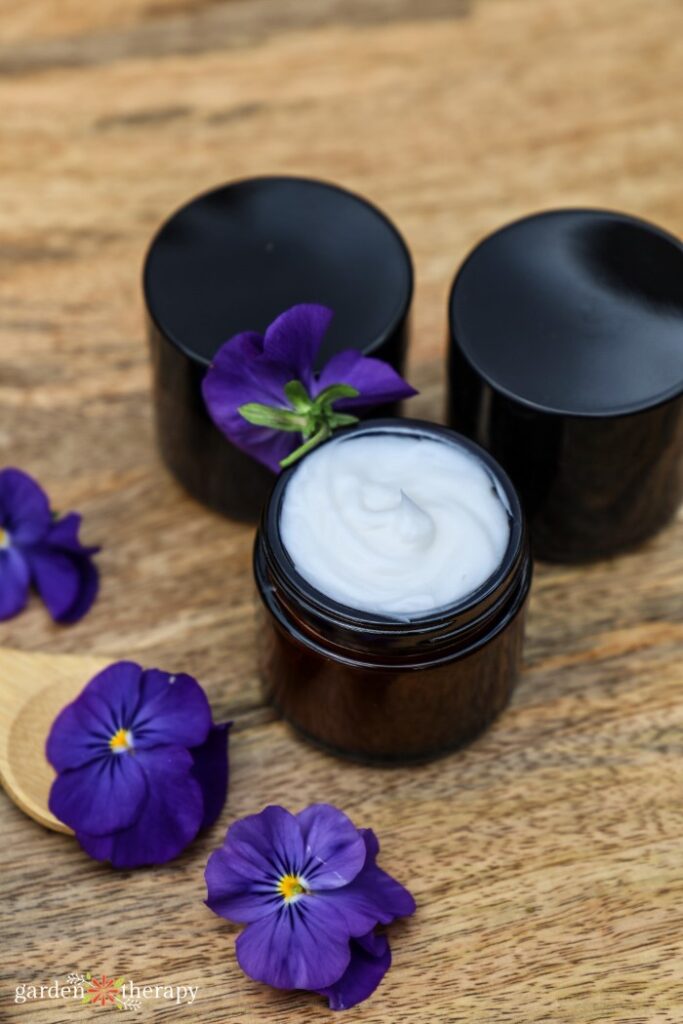 3 glass jars filled with DIY hand cream surrounded by florals