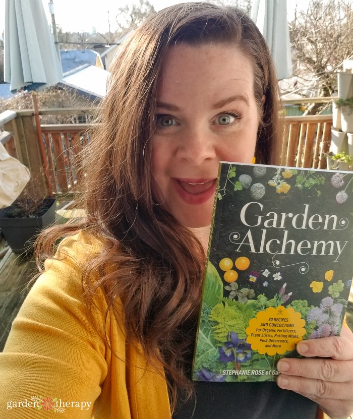 Author Stephanie Rose holding her book, Garden Alchemy