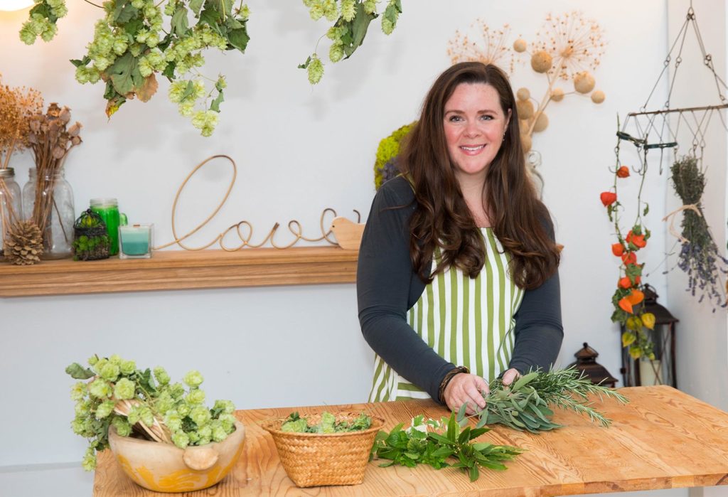 Stephanie standing at a table with bundles of herbs