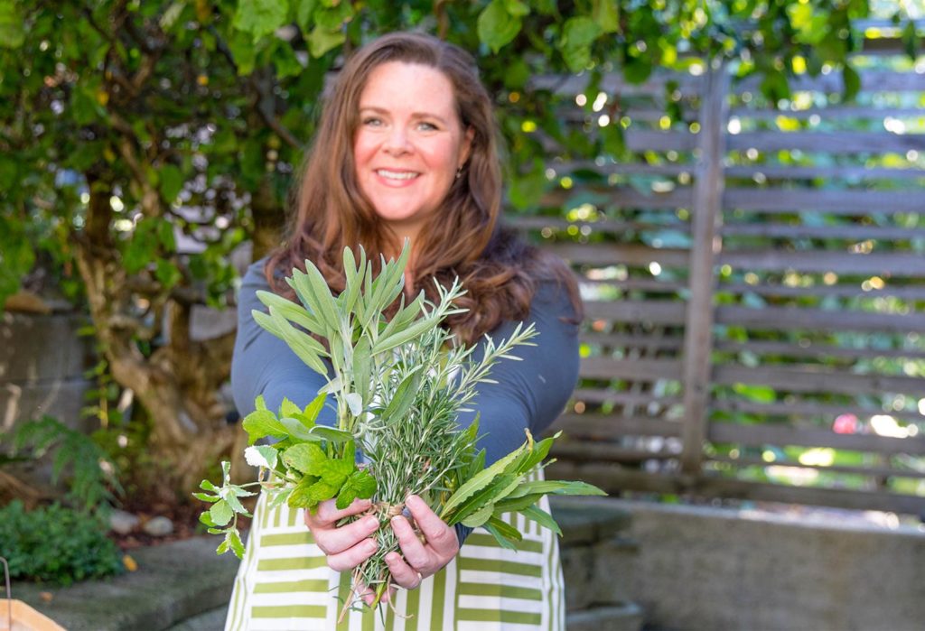 Stephanie holding a bunch of freshly cut herbs