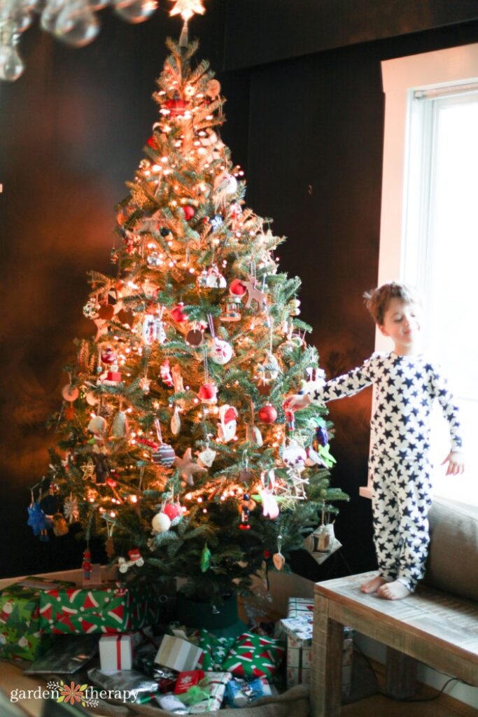 kiddo in pajamas next to decorated Christmas tree