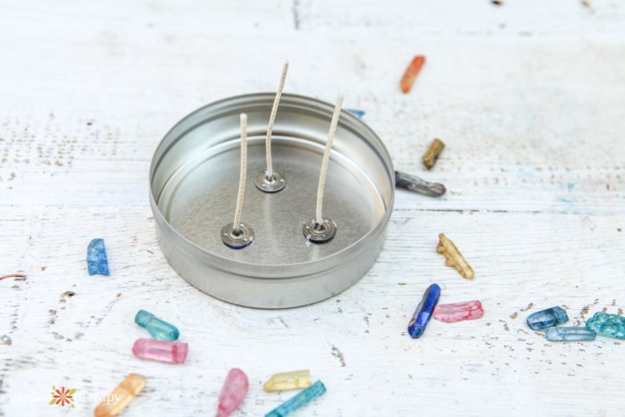 crystals for candles next to an empty wax tin that has wicks glued in it