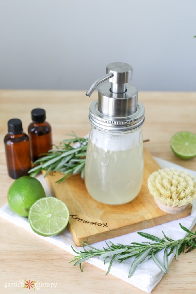 lime and rosemary foaming soap on a wooden board with fresh rosemary and lime wedges