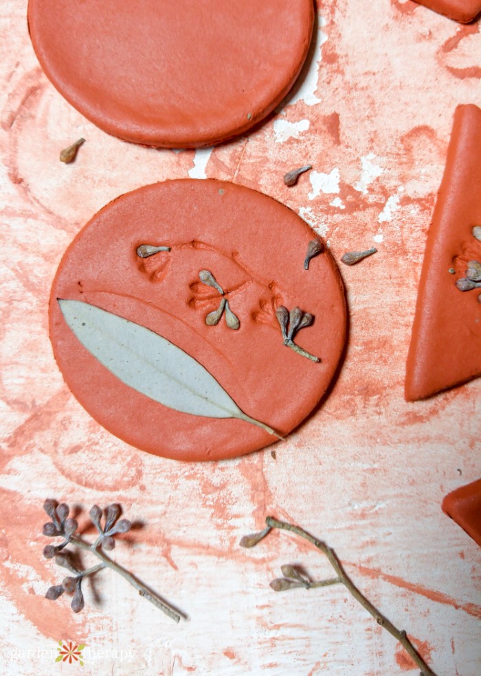 pressing a leaf into a circular clay disk