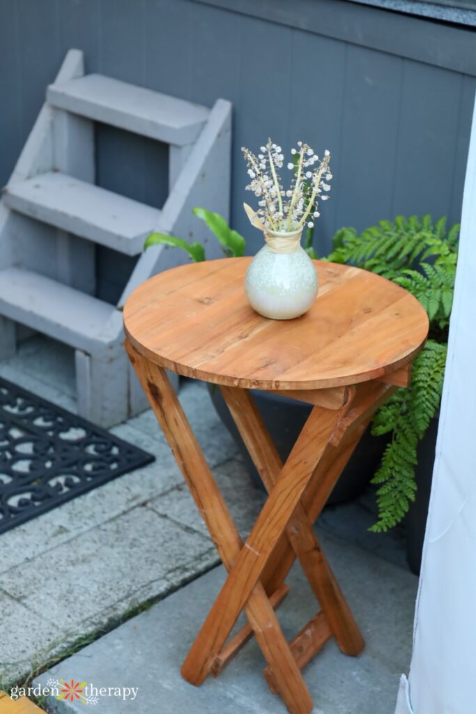 wooden patio side table with vase on top