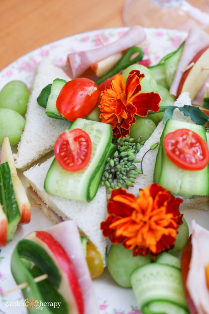 small sandwiches topped with cucumber slices, tomatoes, and edible flowers