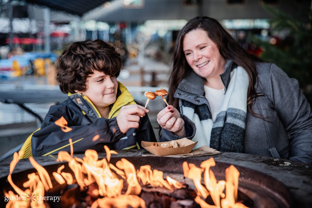 Stephanie and kiddo eating food by the fire