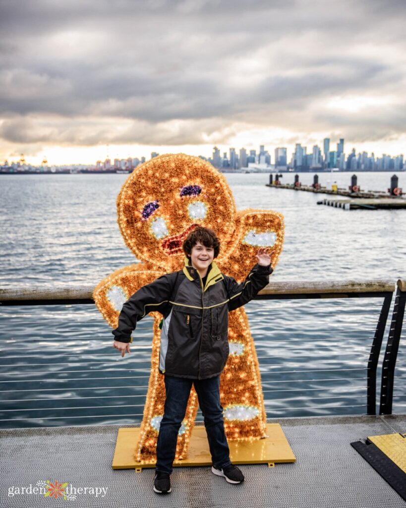 kiddo posing with the gingerbread man with the view of the ocean behind them