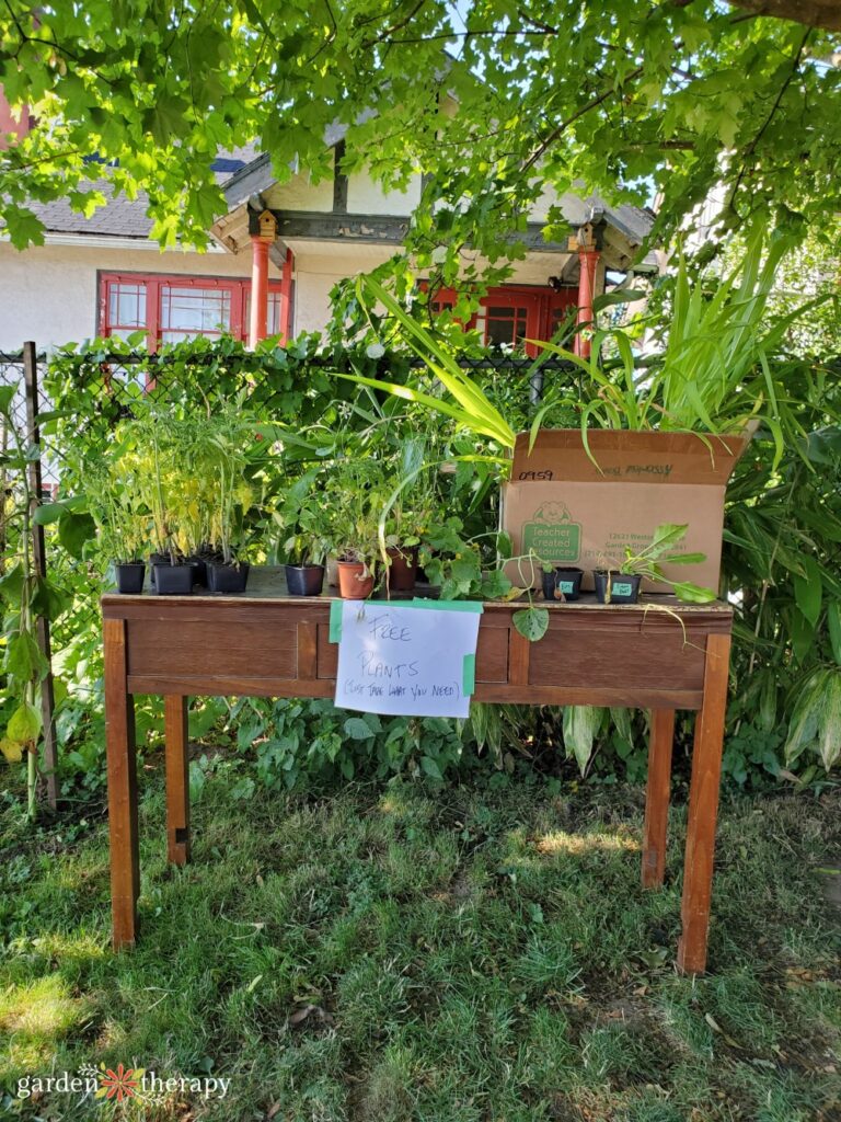 Free plants sign on a table full of potted plants in a front yard