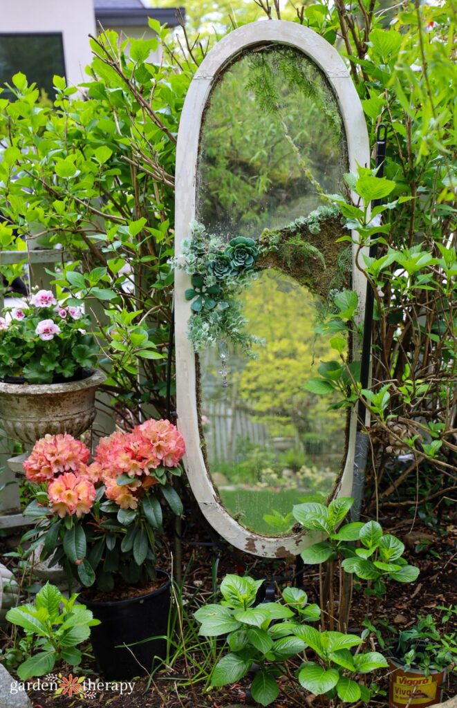 cracked mirror hanging outside with faux succulents inside the crack