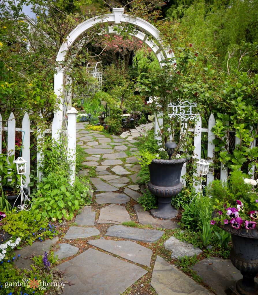 white picket fence and trellis over flagstone path