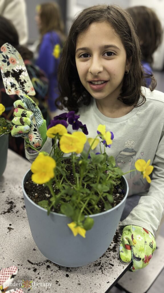 Girl Guide posing with her lily bulb planter with pansies